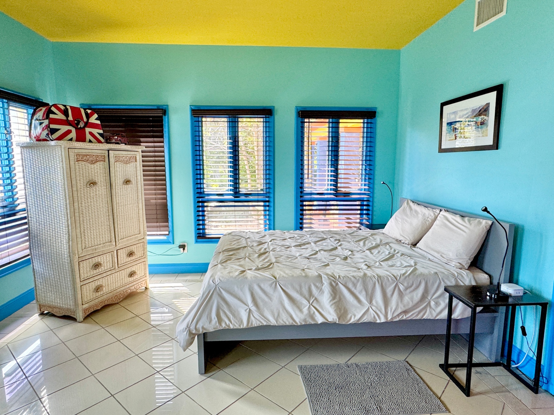 Teal bedroom with yellow ceiling and blue-framed windows