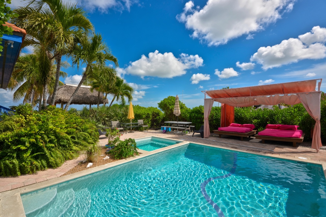 Poolside cabana with pink lounge beds and tropical landscaping