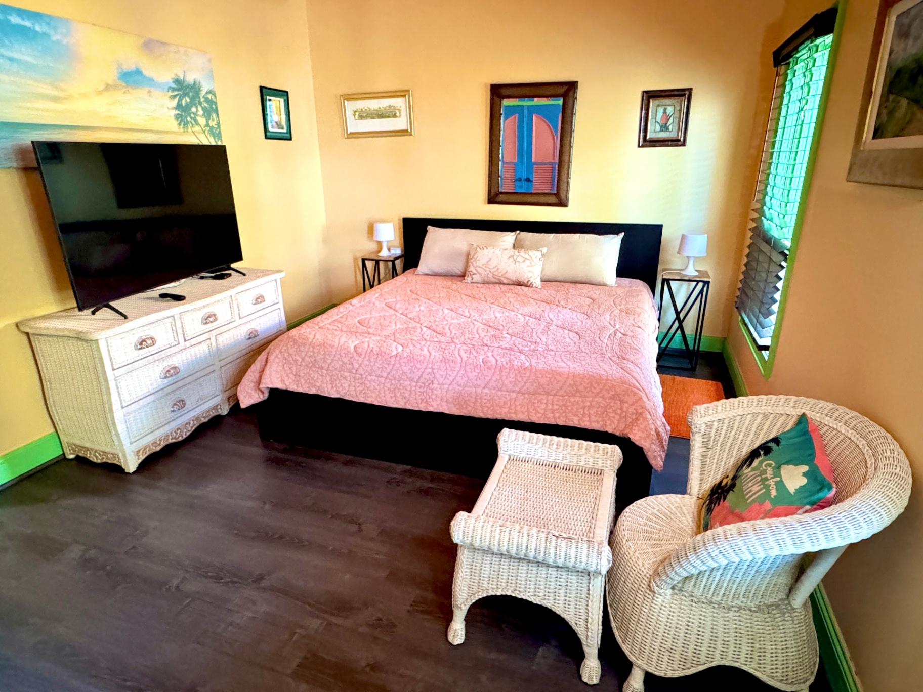 King bedroom with pink bedding, yellow walls and tropical art