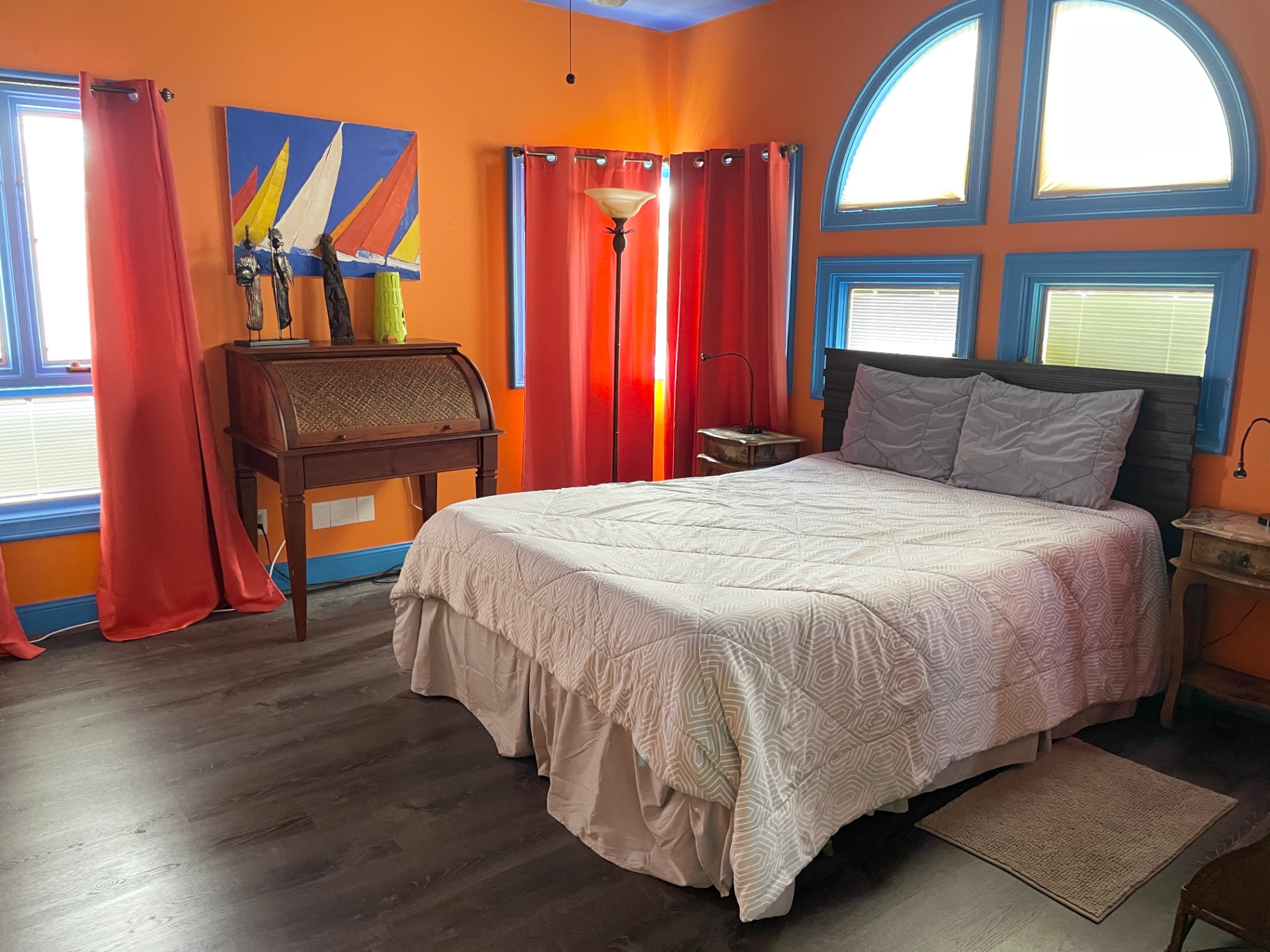 Orange bedroom with arched blue-framed windows and red curtains